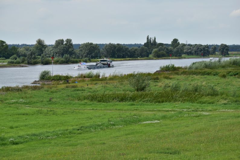 Rural Transport - a boat traveling down a river next to a lush green field