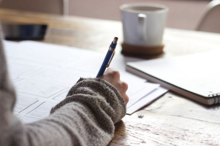 Career Launch - person writing on brown wooden table near white ceramic mug