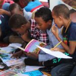 Learning Logistics - boy in blue and white plaid shirt reading book