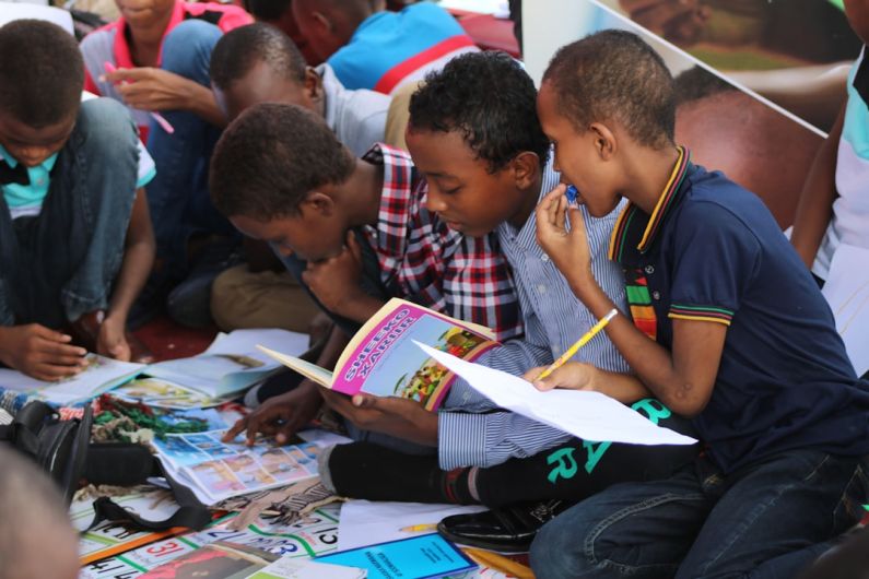 Learning Logistics - boy in blue and white plaid shirt reading book