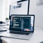 Tech Skills - A MacBook with lines of code on its screen on a busy desk