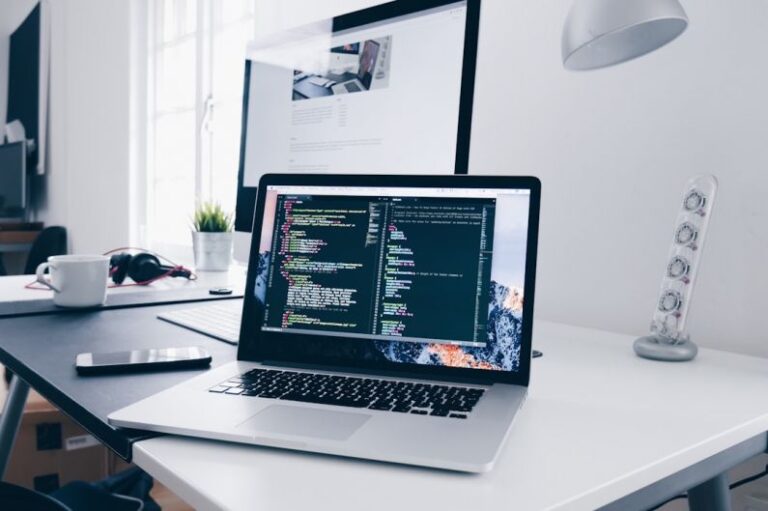 Tech Skills - A MacBook with lines of code on its screen on a busy desk