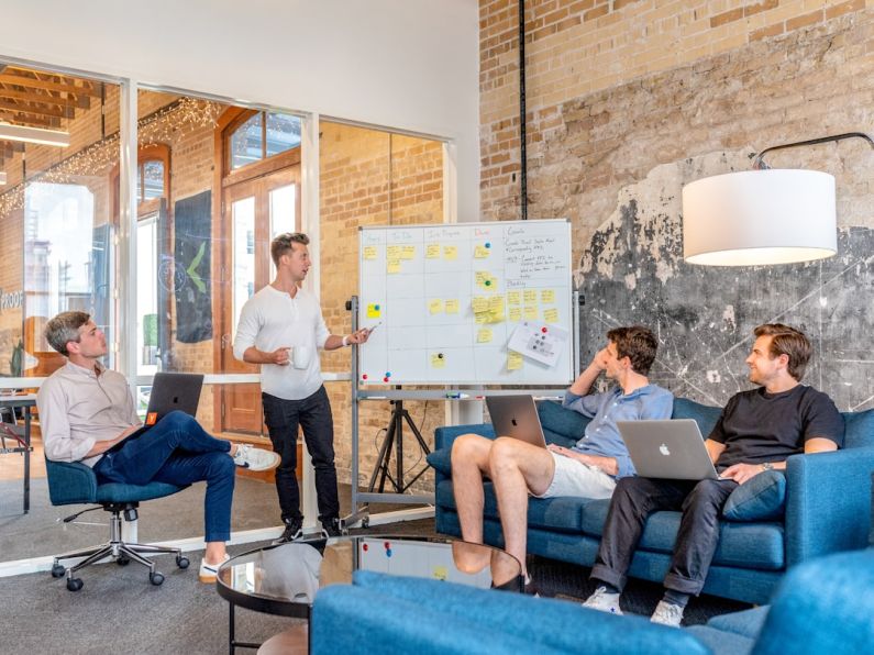 Jobs Future - three men sitting while using laptops and watching man beside whiteboard