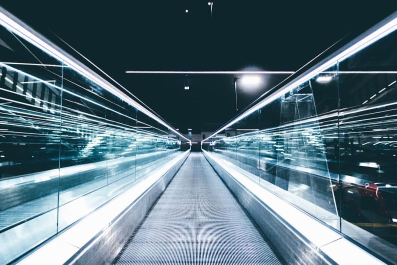 Freight Future - gray conveyor between glass frames at nighttime